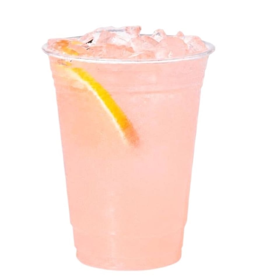 Pink blended beverage in a clear plastic cup, garnished with a lemon wedge and topped with crushed ice.