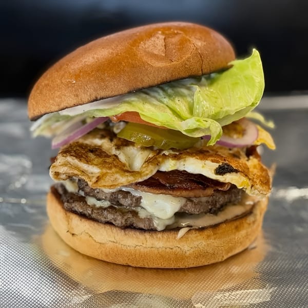 Refuel at The Station's burger with two patties, cheese, fried egg, bacon, lettuce, onion, and pickles.